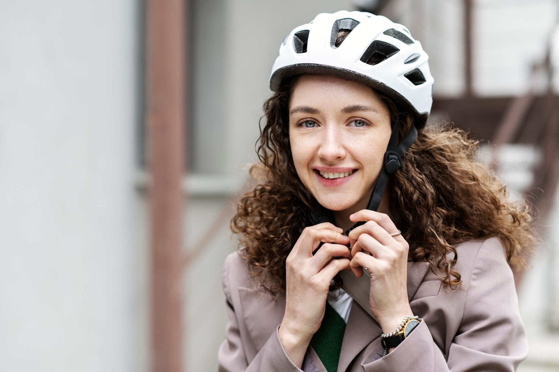 Kvinna med lockigt hår spänner hakbandet på en vit cykelhjälm