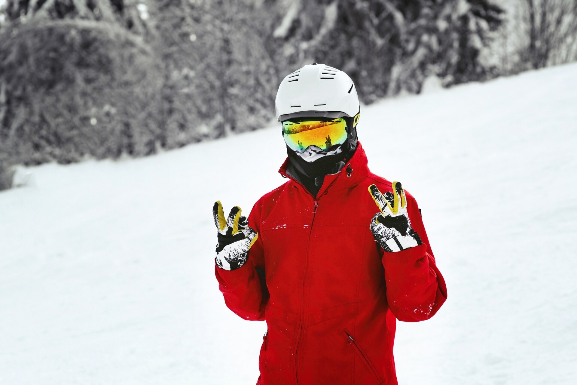Snowboardåkare i vit hjälm och röd jacka i backen