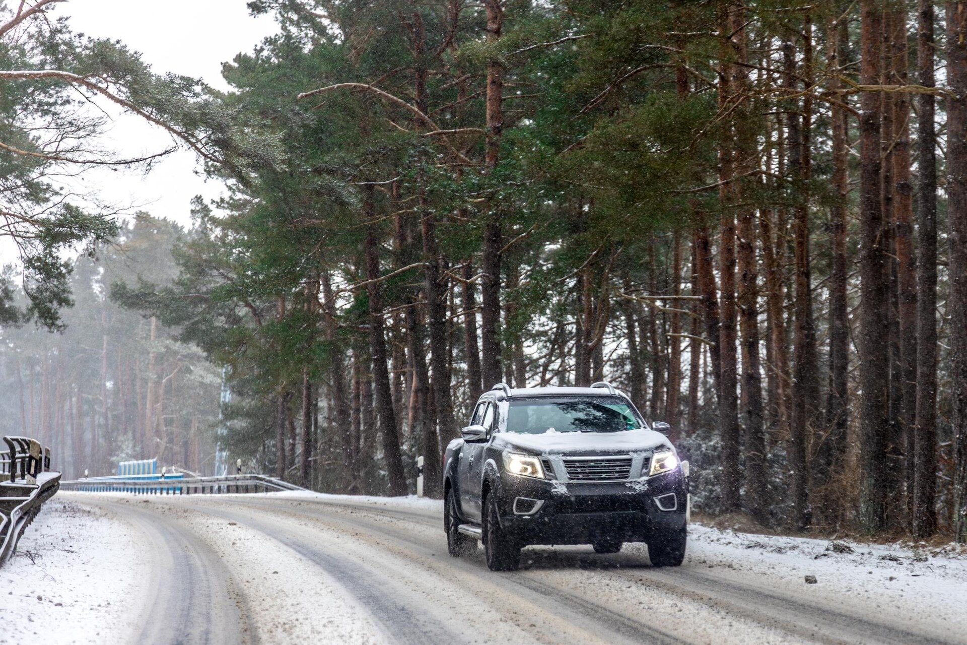 SUV kör på snöig skogsväg i en kurva