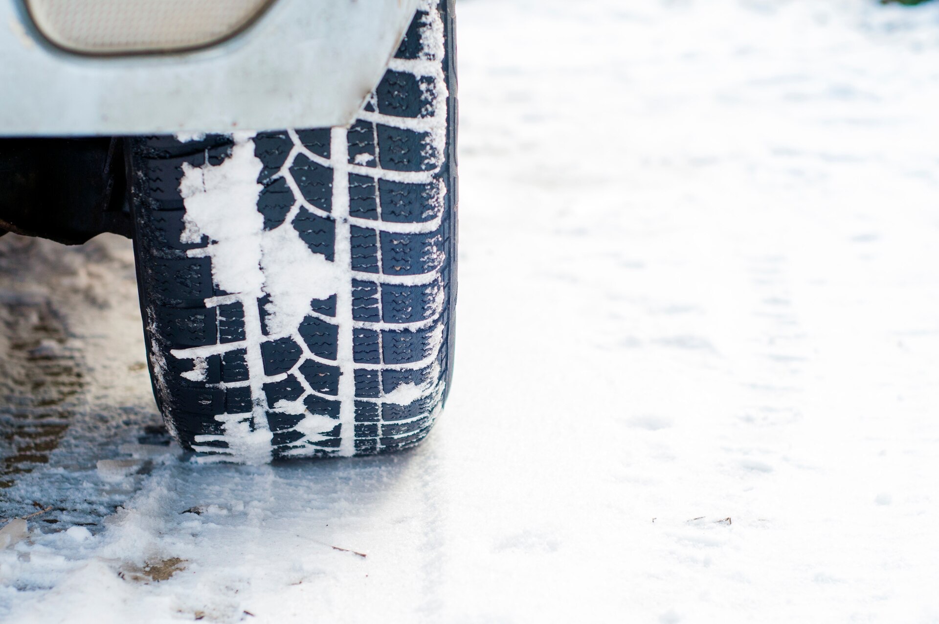 Vinterdäck med snö i mönstret på en vit väg